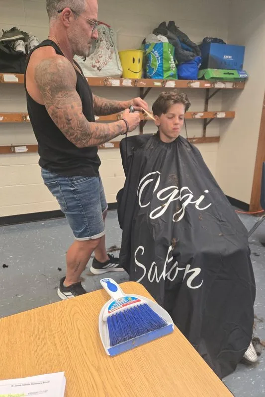 A barber giving a young person a free haircut at a community outreach night.