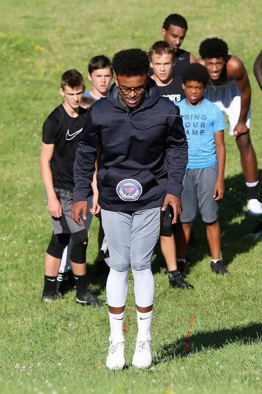 A group of teenagers standing together on a field after a program session.