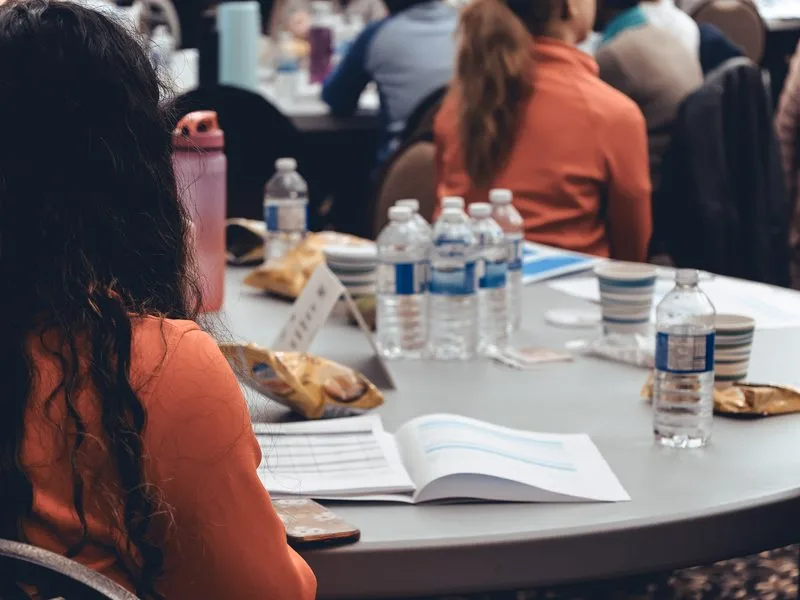 A group seated around a round table during a leadership training session, an open workbook in the foreground.